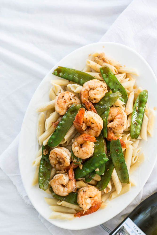 Pasta with prawns and snow peas on white plate
