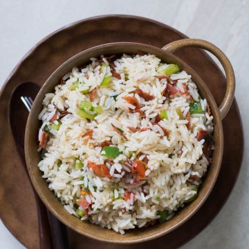 Stir fried rice with salami, sun dried tomatoes in brown bowl