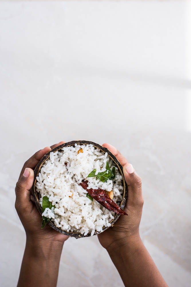 Hand holding coconut rice inside coconut shell