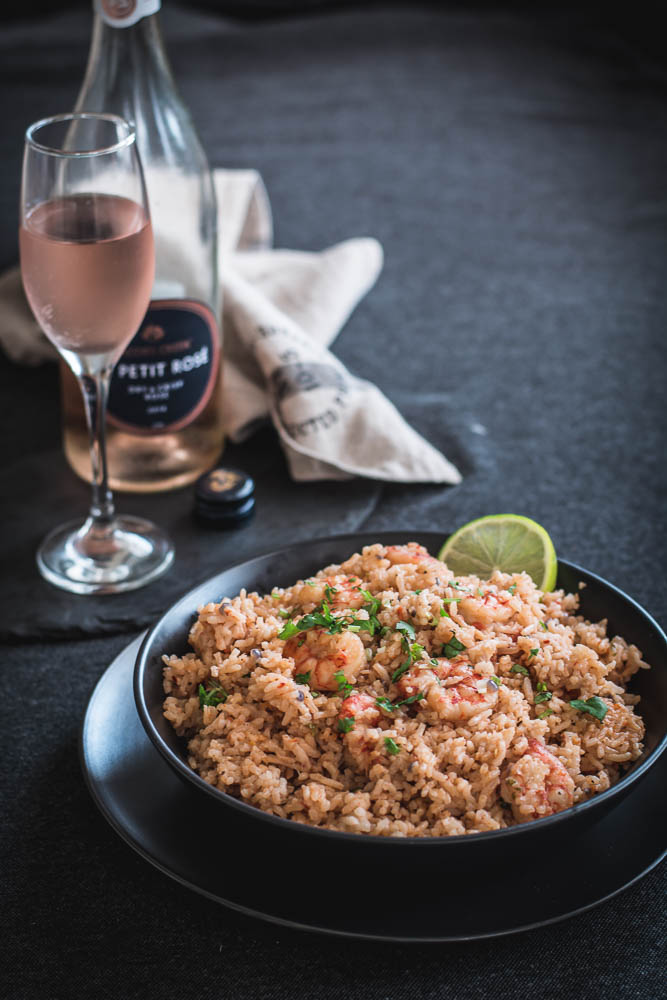 Prawn pilaf in black bowl with a glass of rose on the side