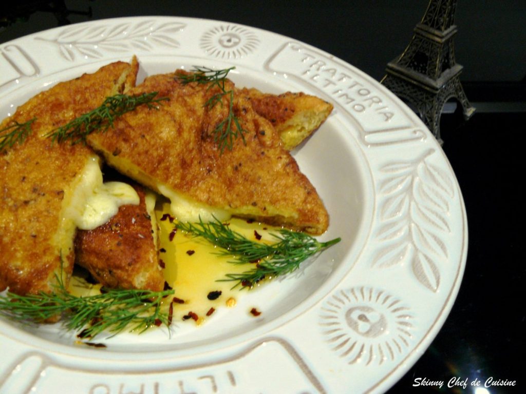 Fried bread triangles filled with cheese served with dill leaves in white plate