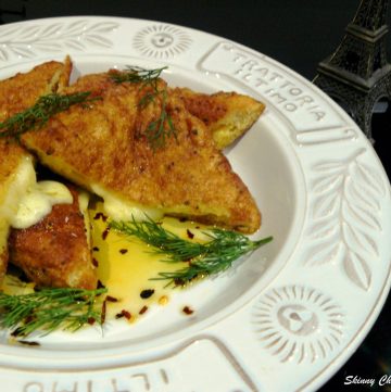 Fried bread triangles filled with cheese served with dill leaves in white plate