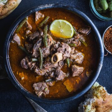 Iraqi meat stew in black bowl with bread on the side