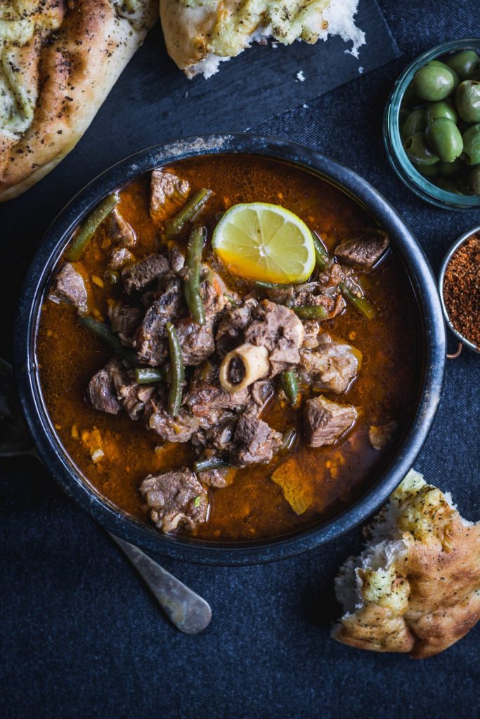 Iraqi meat stew in black bowl with bread on the side