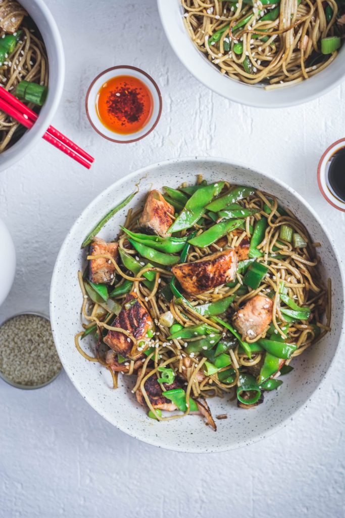 Soba noodles with salmon, snow peas in white bowl