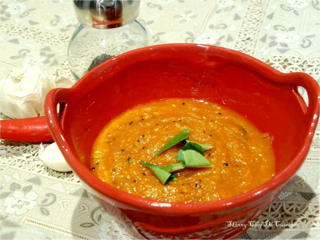 Garlic chutney garnished with curry leaves in red bowl