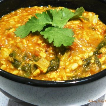 Indian lentil curry with greens in black bowl