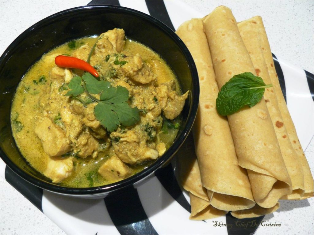 Malaysian style chicken curry in black bowl with flatbreads on the side