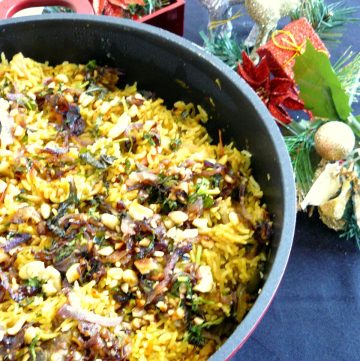 Lamb biryani served on grey plate with Christmas decorations in the background