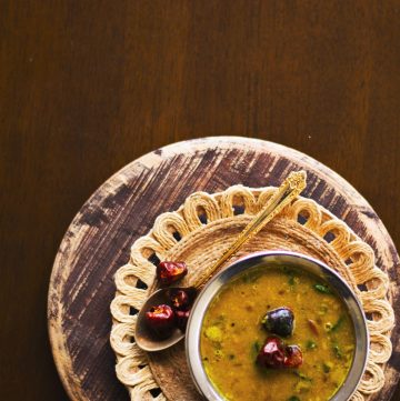 Spinach and lentil curry served in copper pot on a brown background