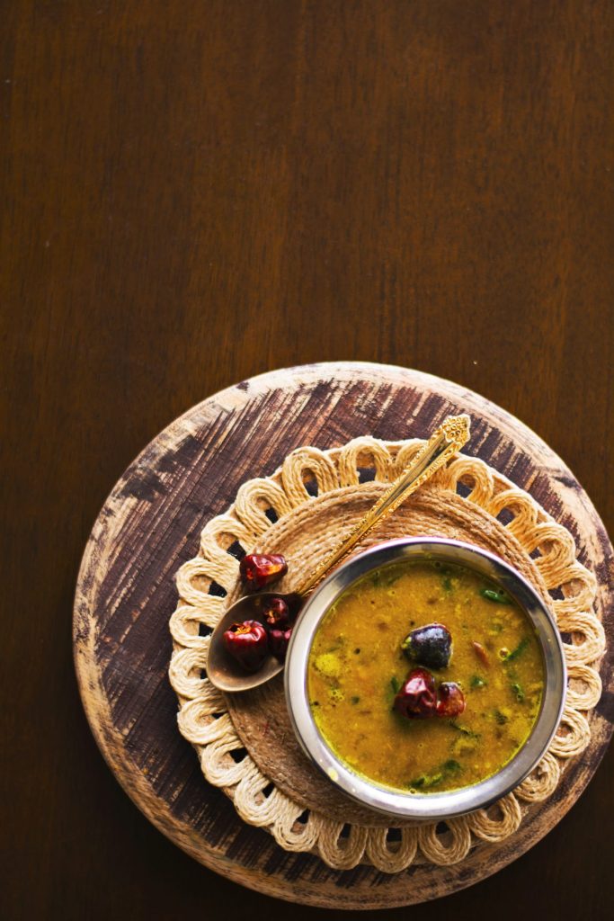 Spinach and lentil curry served in copper pot on a brown background