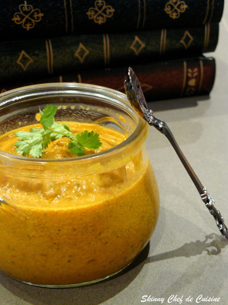 Tomato onion chutney in glass jar with a spoon on the side