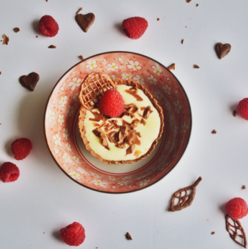 White chocolate mousse in chocolate cup garnished with raspberries and chocolate hearts