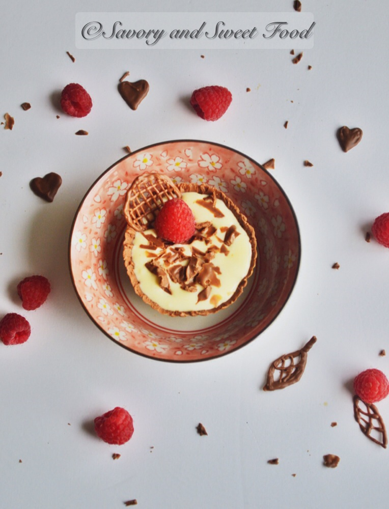 White chocolate mousse in chocolate cup garnished with raspberries and chocolate hearts