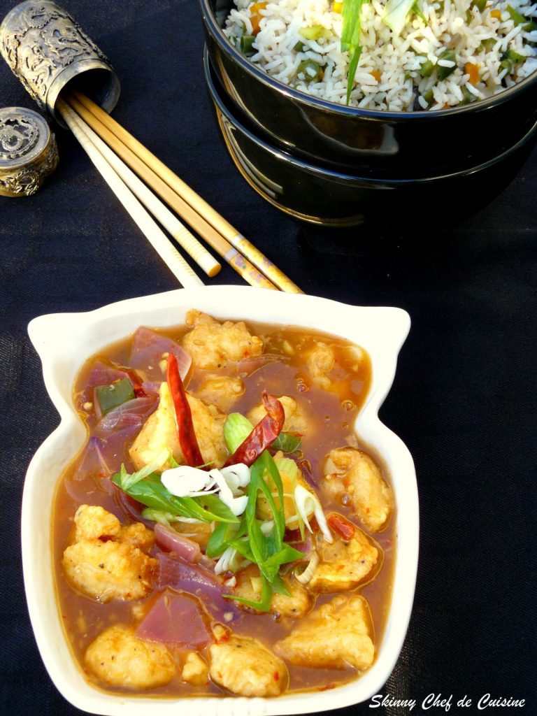 Indo Chinese style chicken garnished with spring onions and dried chillies served in white bowl