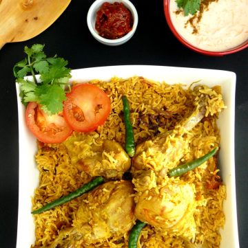 Chicken biryani garnished with tomato slices and green chillies served in white bowl