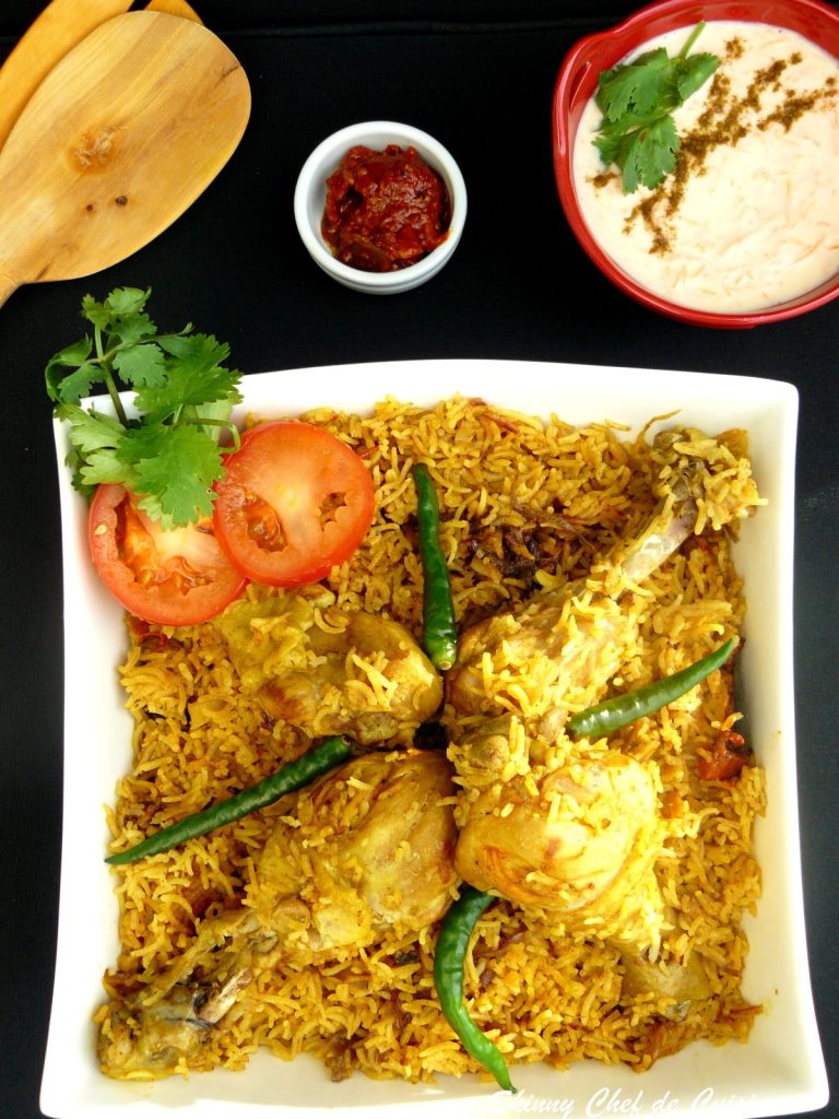 Chicken biryani garnished with tomato slices and green chillies served in white bowl