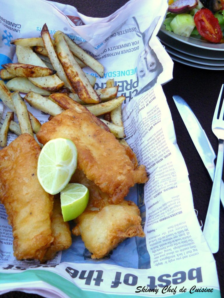 Batter fried fish with chips and lime wedges served in newspaper