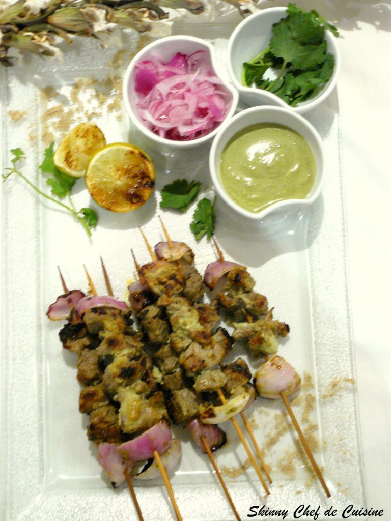 Grilled lamb skewers served with lime wedges, pickled onions and mint chutney