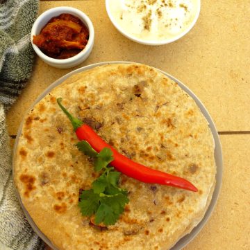 A stack of onion stuffed flatbreads with a red chilli on top