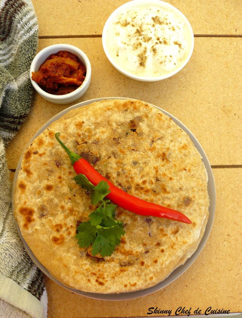 A stack of onion stuffed flatbreads with a red chilli on top