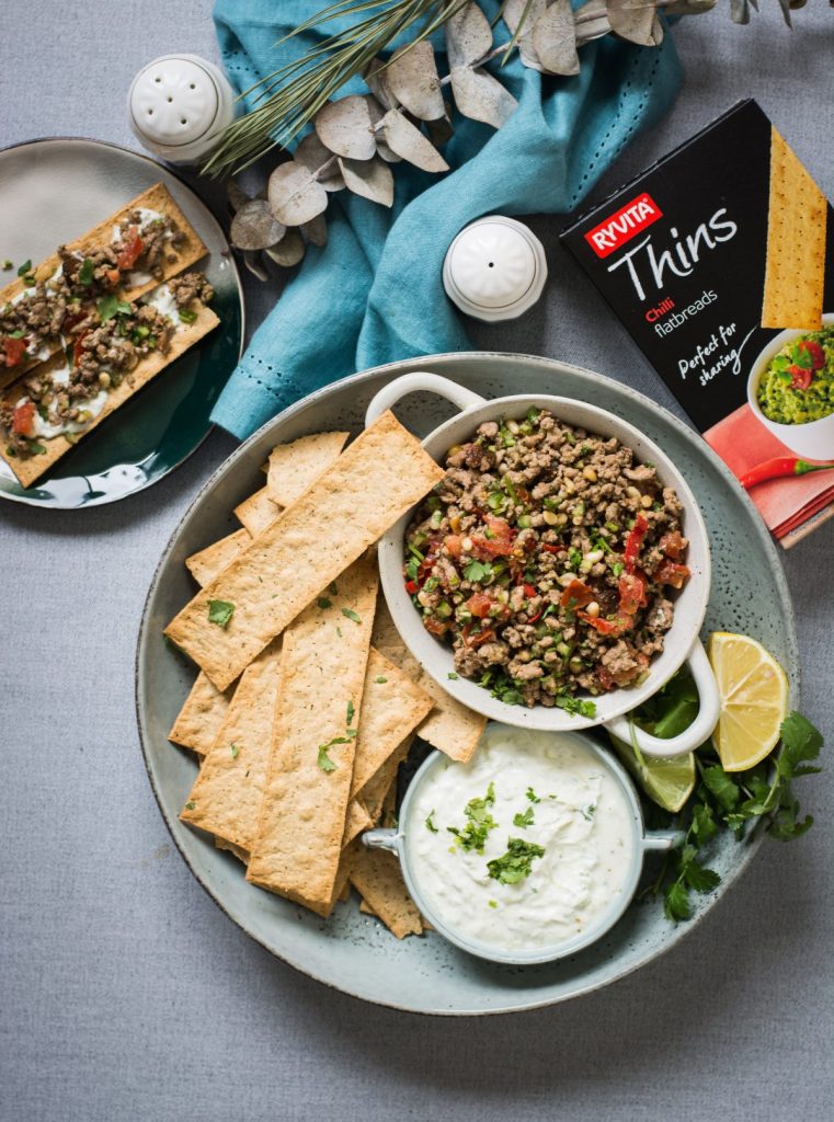 Moroccan lamb salad in white bowl along with crackers and yoghurt dip