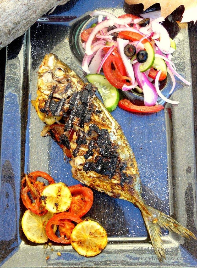 Grilled whole fish with lemon slices and salad