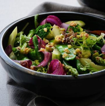 Green salad with shaving of purple carrot in black bowl