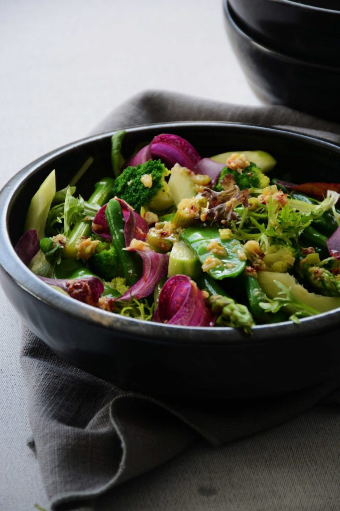 Green salad with shaving of purple carrot in black bowl