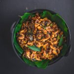 dried shrimp with caramelized onions served on green leaf in black bowl