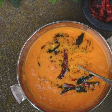 A steel bowl with tomato curry