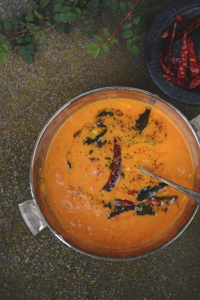 A steel bowl with tomato curry