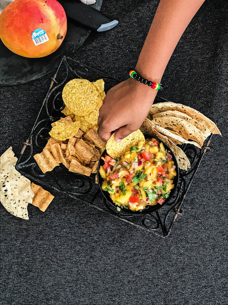 Hand dipping cracker into mango salsa