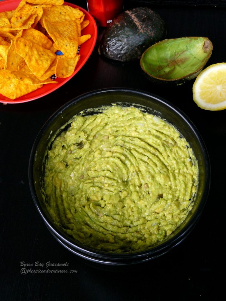 Guacamole in black bowl with tortilla chips on the side