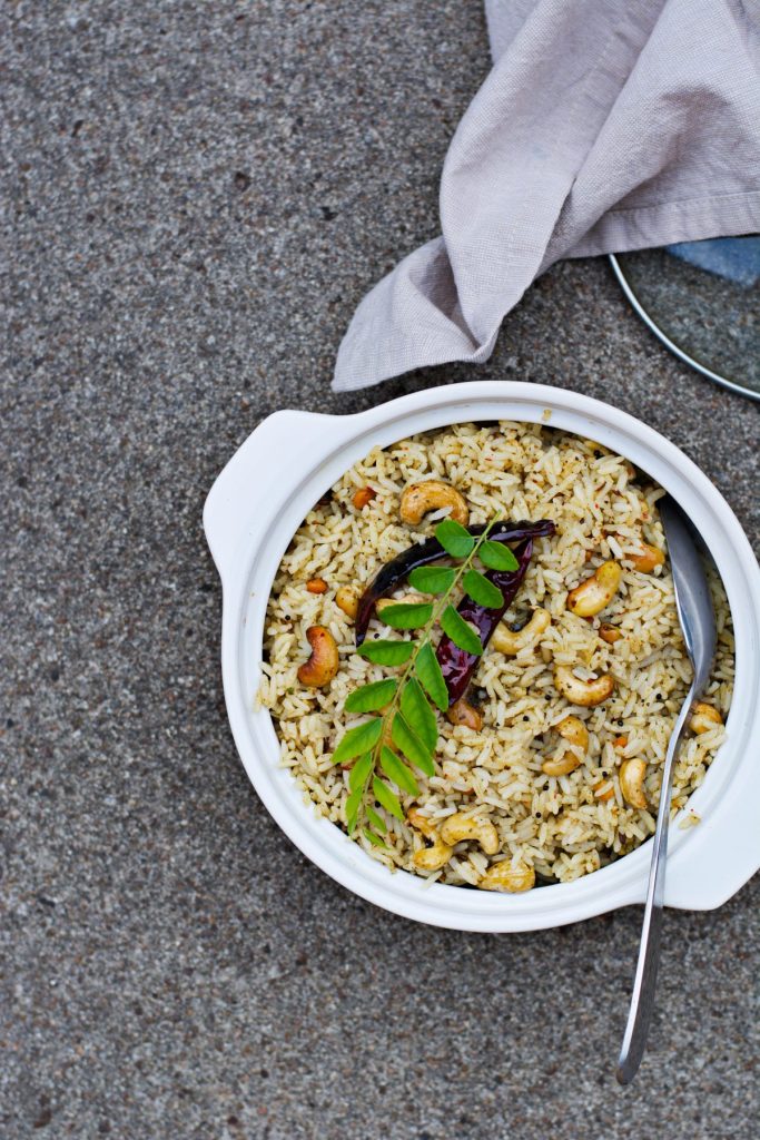 Curry leaf rice garnished with cashewnuts and fresh curry leaves served in white bowl