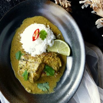 Indian fish curry served with rice in a black bowl
