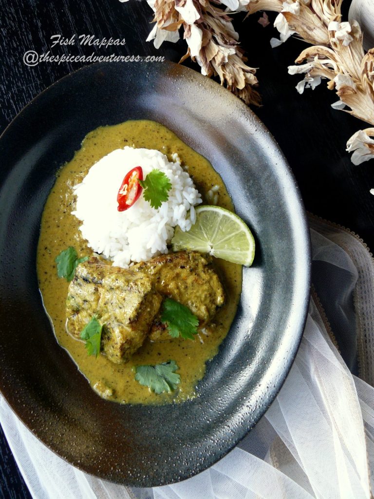 Indian fish curry served with rice in a black bowl