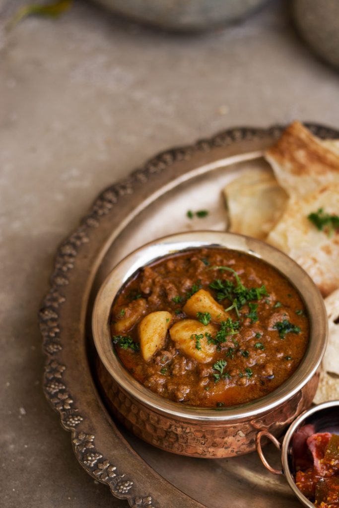 Potato and minced meat curry served in copper pot