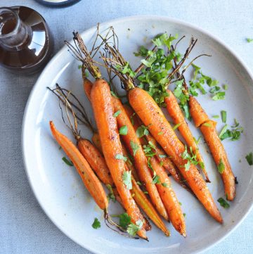 Whole roasted carrots served on grey plate