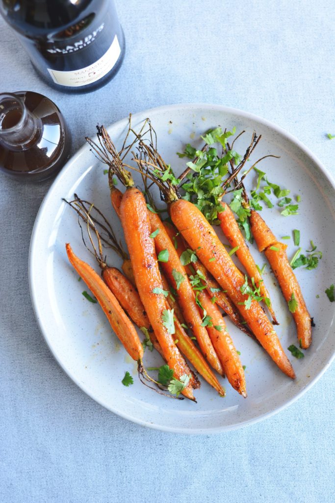 Whole roasted carrots served on grey plate