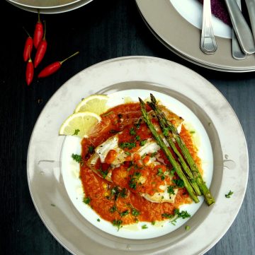 Pan fried fish, tomato sauce and grilled asparagus served on grey plate