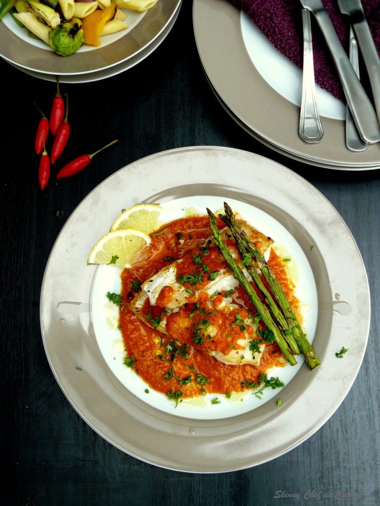 Pan fried fish, tomato sauce and grilled asparagus served on grey plate