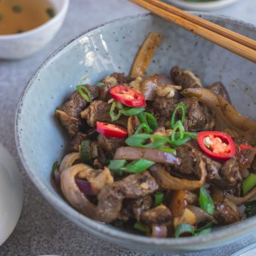 Indo Chinese style lamb fry in blue bowl with chopsticks on the side