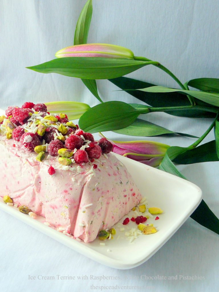 Ice Cream terrine with raspberries, white chocolate and pistachios served on white platter