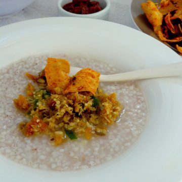 Rice gruel topped with dry shark chutney and pappadums served in white bowl