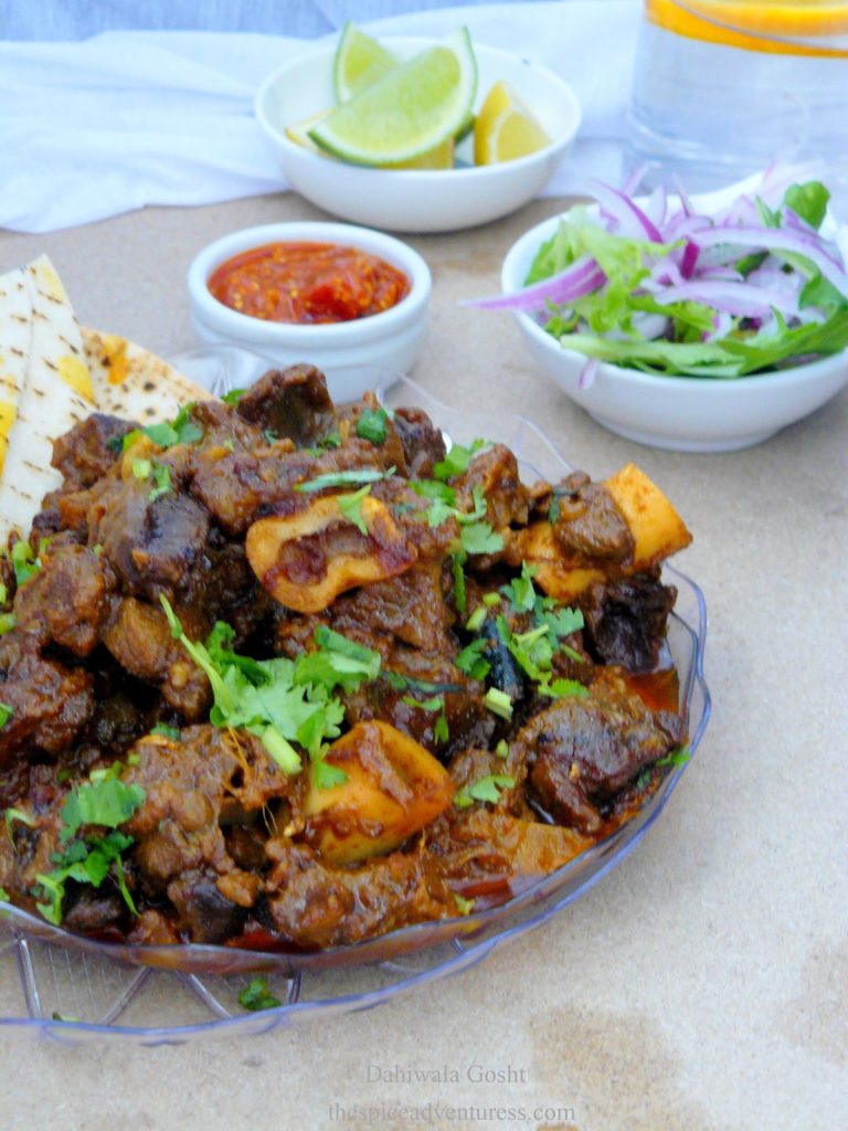 Lamb curry served on plate with salad and lemon wedges on the side