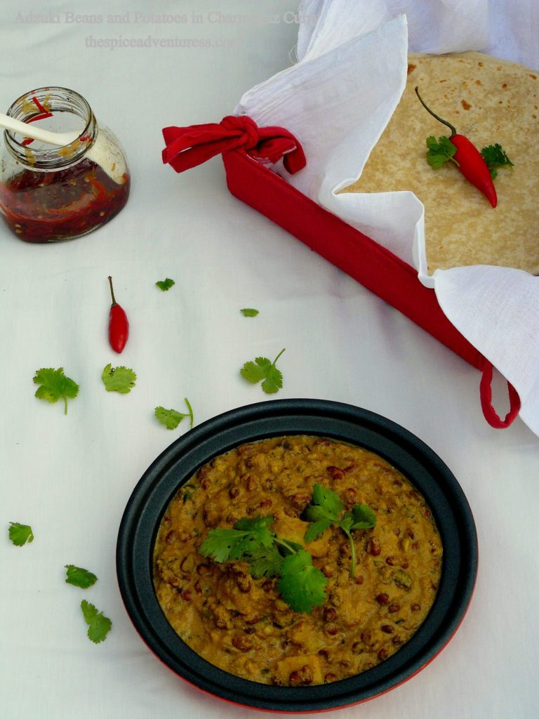 Adzuki beans and potato curry served in black bowl with flatbreads on the side