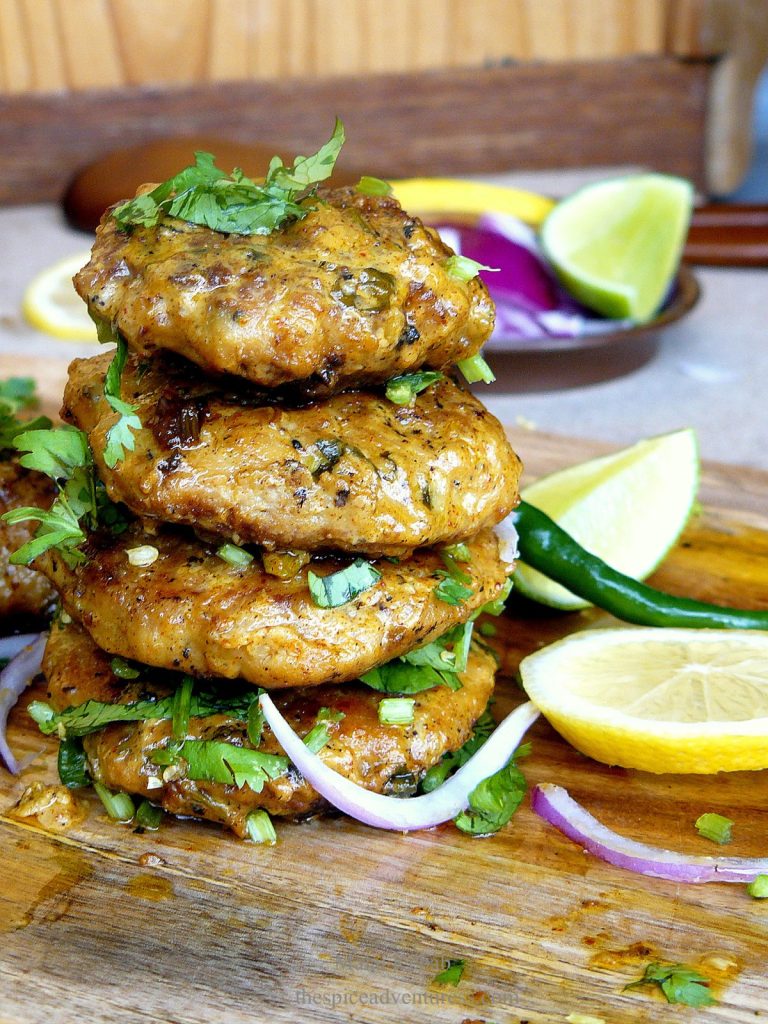 A stack of four chicken kebabs with lemon wedges on the side