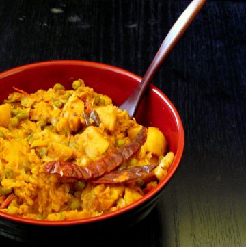 Indian style cabbage, potato, peas stir fry served in red and black bowl