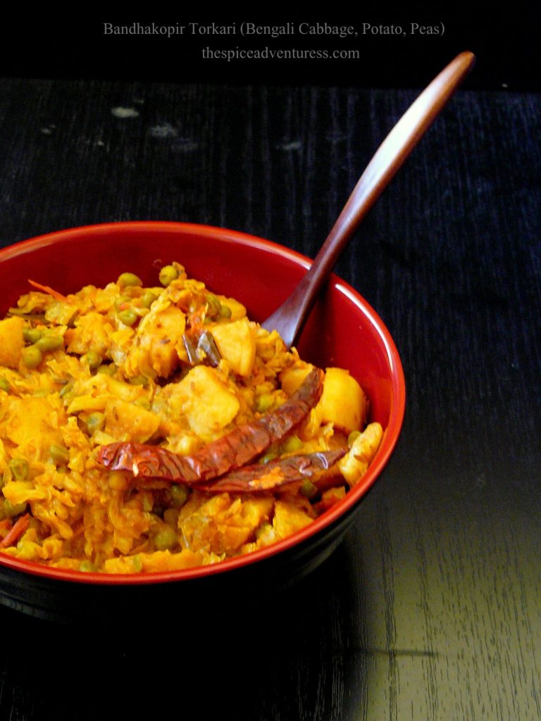 Indian style cabbage, potato, peas stir fry served in red and black bowl